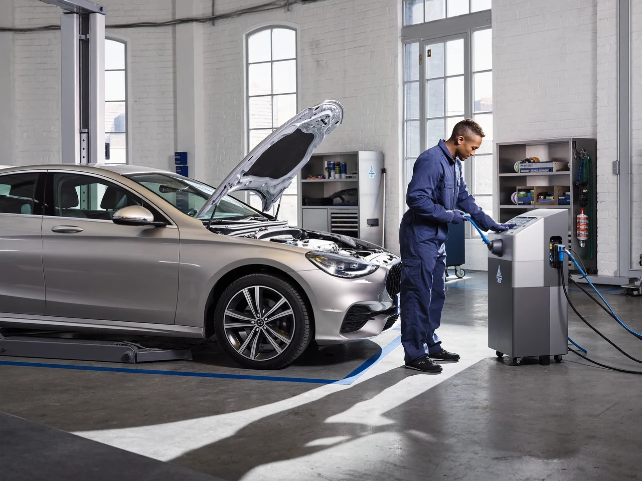 Helle Werkstatt mit geöffneter Motorhaube und vorbereiteter Klima-Servicestation